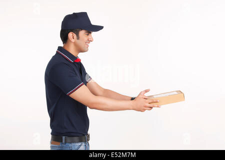 Vue latérale du package delivery man giving against white background Banque D'Images