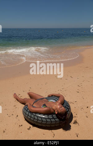 Jeune femme de soleil et obtenir un bronzage sur la plage, Algarve Portugal Europe Banque D'Images
