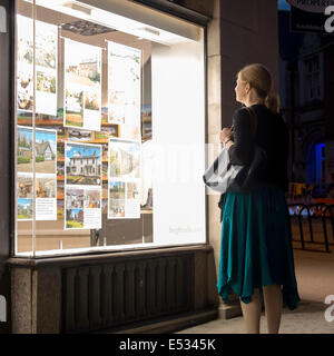 Femme à la fenêtre d'un des agents immobiliers dans la nuit, au Royaume-Uni. Banque D'Images