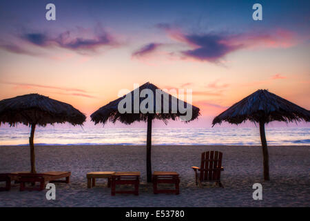 Palapas dans twilight glow à Playa La Punta, Puerto Escondido, Oaxaca, Mexique. Banque D'Images