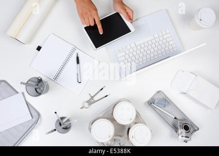 High angle shot d'un bureau blanc principalement avec des objets du bureau blanc et argent, avec a woman holding a tablet computer Banque D'Images