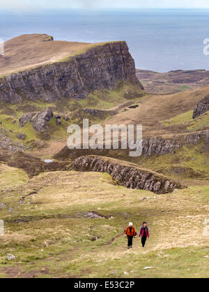 Deux marcheurs sur les pentes de Meall na Suiramach avec des rochers de montagne près de Flodigarry au-delà, Trotternish, île de Skye, Écosse, Royaume-Uni Banque D'Images