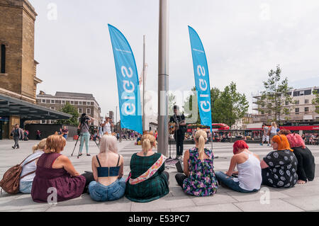 La gare de King's Cross, Londres, Royaume-Uni, le 19 juillet 2014. De jeunes musiciens en compétition lors du lancement de concerts Big Busk, the UK's biggest street music competition. Le gagnant sera couronné musicien ambulant de l'année. L'événement est organisé par le maire de Londres et fait partie de la campagne # BackBusking. Sur la photo : Zack Thompson, de Croydon, playing acoustic guitar devant un auditoire sur un enterrement de vie de nuit. Crédit : Stephen Chung/Alamy Live News Banque D'Images