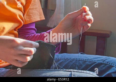 Close up of young woman's hands certains couture tissu avec une aiguille et du fil Banque D'Images