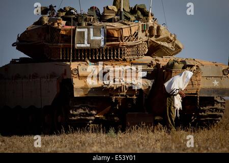 Frontière de Gaza, l'opération de protection. 19 juillet, 2014. Un soldat israélien prie à côté d'un tank Merkava dans le sud d'Israël près de la frontière avec Gaza, le 12e jour de l'opération de protection, le 19 juillet 2014. Deux soldats israéliens ont été tués dans un échange de feu avec des militants palestiniens israéliens qui avait infiltré à travers un tunnel de Gaza gazon plus tôt le samedi, les forces de défense israéliennes (FDI) ont confirmé dans une déclaration. Source : Xinhua/JINI/Alamy Live News Banque D'Images