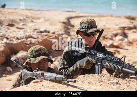 Au sol et d'autodéfense japonaise US Marine nageur scout soldats opération spéciale de tenir la plage tout en pratiquant les techniques de niveau de petites unités dans le cadre du Programme d'échange d'observateur du Japon à Kin Blue Beach 16 juillet 2014 à Okinawa, au Japon. Banque D'Images