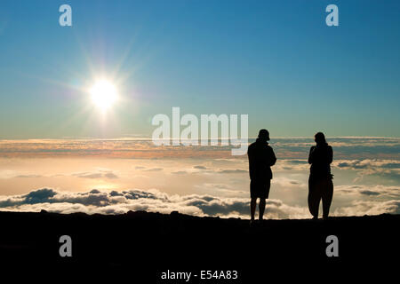 Silhouette touristiques regardant le coucher du soleil sur le sommet de volcan Haleakala sur Maui Hawaii Banque D'Images