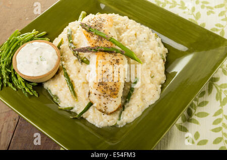 Flétan au risotto aux asperges et haricots de mer sur une plaque verte Banque D'Images