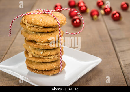 Une pile de beurre de cacahuète cookies faits maison remplie avec ornements rouge en arrière-plan Banque D'Images