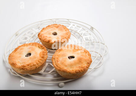 3 petits pâtés à la viande fait maison sur une grille de refroidissement sur un fond pâle tartes individuelles adapté pour un pique-nique (2 de 20 ) Banque D'Images