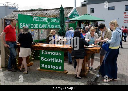 Les gens mangent des fruits de mer frais locaux dans un magasin sur la jetée d'Oban, en Écosse. Banque D'Images