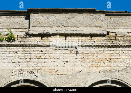 Vieux mur de briques de l'édifice et l'effritement du plâtre. Fragment d'un ciel bleu. Banque D'Images