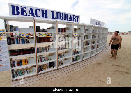 Varna, BGR. 20 juillet, 2014. Les gens recherchent et lire des livres à la première bibliothèque de plage ouvert en Bulgarie à la mer Noire d'Albena Resort, Dimanche, juillet, 20, 2014. En Albena a ouvert la première bibliothèque de plage dans l'Union européenne et la troisième dans le monde et sur ses tablettes sont disposés plus de 2500 volumes dans plus de 10 langues. La bibliothèque est totalement gratuit. Les titres sont soigneusement sélectionnés pour tous les goûts - world classics, suspense, mystère, lectures, romantique mémoires. Les touristes pourront prendre un livre pour libre sans une carte de bibliothèque. Si ils n'ont pas lu le livre qu'ils ont prises, Banque D'Images