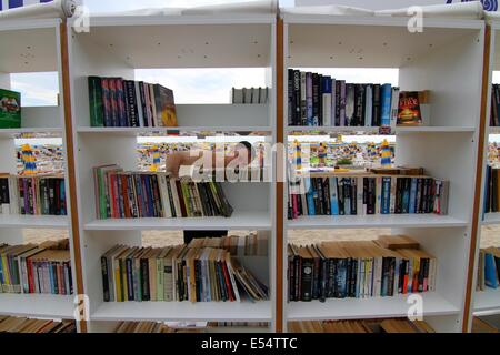 Varna, BGR. 20 juillet, 2014. Les gens recherchent et lire des livres à la première bibliothèque de plage ouvert en Bulgarie à la mer Noire d'Albena Resort, Dimanche, juillet, 20, 2014. En Albena a ouvert la première bibliothèque de plage dans l'Union européenne et la troisième dans le monde et sur ses tablettes sont disposés plus de 2500 volumes dans plus de 10 langues. La bibliothèque est totalement gratuit. Les titres sont soigneusement sélectionnés pour tous les goûts - world classics, suspense, mystère, lectures, romantique mémoires. Les touristes pourront prendre un livre pour libre sans une carte de bibliothèque. Si ils n'ont pas lu le livre qu'ils ont prises, Banque D'Images