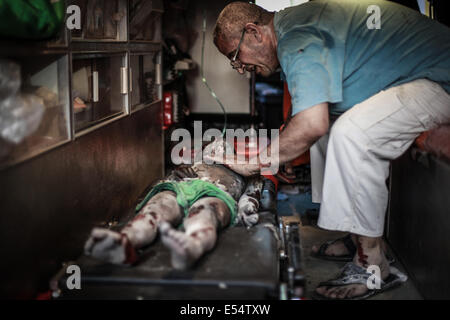 Gaza, Territoires palestiniens. 20 juillet, 2014. Les Palestiniens d'évacuer une victime d'un bâtiment qui a été touchée par une frappe israélienne à Gaza, le 20 juillet 2014. Frappes israéliennes sur Gaza le 20 juillet a tué au moins 97 personnes. Le Conseil de sécurité de l'ONU a appelé à un ''cessez-le-feu immédiat'' comme Israël pressé au moyen d'un assaut sur Gaza en prenant le nombre de morts palestiniens au-dessus de 500. Credit : Hosam Salem/NurPhoto/ZUMA/Alamy Fil Live News Banque D'Images