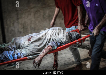 Gaza, Territoires palestiniens. 20 juillet, 2014. Les Palestiniens d'évacuer une victime d'un bâtiment qui a été touchée par une frappe israélienne à Gaza, le 20 juillet 2014. Frappes israéliennes sur Gaza le 20 juillet a tué au moins 97 personnes. Le Conseil de sécurité de l'ONU a appelé à un ''cessez-le-feu immédiat'' comme Israël pressé au moyen d'un assaut sur Gaza en prenant le nombre de morts palestiniens au-dessus de 500. Credit : Hosam Salem/NurPhoto/ZUMA/Alamy Fil Live News Banque D'Images