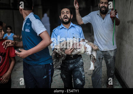 Gaza, Territoires palestiniens. 20 juillet, 2014. Les Palestiniens d'évacuer une victime d'un bâtiment qui a été touchée par une frappe israélienne à Gaza, le 20 juillet 2014. Frappes israéliennes sur Gaza le 20 juillet a tué au moins 97 personnes. Le Conseil de sécurité de l'ONU a appelé à un ''cessez-le-feu immédiat'' comme Israël pressé au moyen d'un assaut sur Gaza en prenant le nombre de morts palestiniens au-dessus de 500. Credit : Hosam Salem/NurPhoto/ZUMA/Alamy Fil Live News Banque D'Images