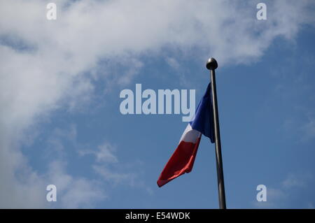 Bleu, rouge, blanc drapeau triclour français contre un ciel bleu avec son coin rouge qui souffle dans la brise vers les nuages blancs Banque D'Images