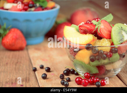 Savoureuse salade de fruits frais dans le bol sur la table en bois Banque D'Images