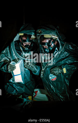 Les soldats de la garde nationale de l'armée américaine portant des combinaisons HAZMAT encapsulant identifier un agent radiologique potentiel pendant un exercice de formation à l'Université de Marie 6 Mai, 2014 à Bismarck, Dakota du Nord. Banque D'Images
