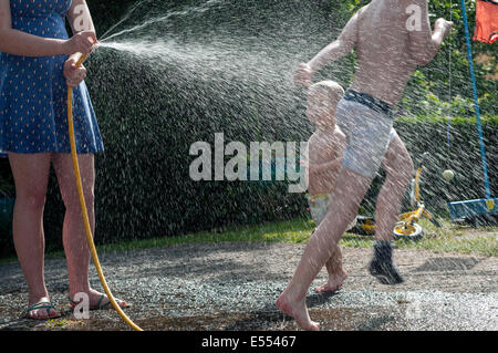 Enfants jouant dans l'eau,canicule Britains, enfant, jardin, jeu, enfant, sprinkleur, pelouse, éclabousser, splash, l'été, spray, vert, Banque D'Images