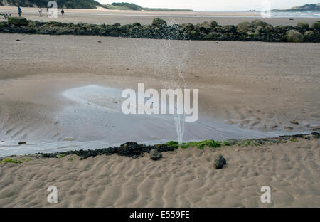 Une fuite d'un tuyau d'évacuation de pulvériser de l'eau sale sur une plage. Banque D'Images