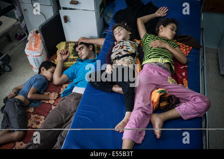 La bande de Gaza. 21 juillet, 2014. Les membres de famille palestinienne Fayyam attendre à voler loin de Beith Hannoun pour une école de l'ONU à Cheikh a dit qu'ils étaient des centaines de personnes sont à l'abri des bombardements. Fuir les Palestiniens le Beit Hannoun voisinage pendant les bombardements israéliens dans la bande de Gaza, Territoires palestiniens. Credit : Ibrahim Khader/Pacific Press/Alamy Live News Banque D'Images