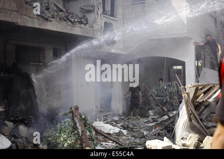 La bande de Gaza. 21 juillet, 2014. Les pompiers essaient d'éteindre un feu dans une des maisons que les avions ont bombardé après l'armée de l'air israélienne maison appartenant à un membre du Hamas dans le camp de réfugiés de Shati après qu'il a été lancé par trois roquettes et des avions israéliens ont bombardé plusieurs cibles dans la bande de Gaza, le lundi, tuant 40 Palestiniens, dont des enfants, ce qui porte le nombre de Palestiniens tués depuis le début de l'offensive sur Gaza à 560 morts et plus de 5 000 blessés et 1 100 maisons détruites. Credit : PACIFIC PRESS/Alamy Live News Banque D'Images