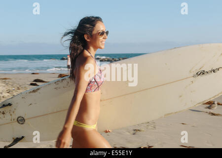 Les jeunes filles en bikini surfeur surf Transport à marcher en direction de ocean Banque D'Images