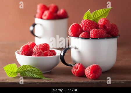 Tasses en émail framboise fraîche sur fond de bois Banque D'Images