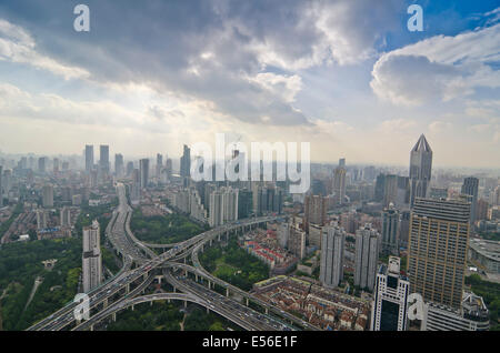 Vue panoramique de la circulation de l'après-midi à l'heure de pointe sur la Yanan Express Way interchange avec la circulation se croisant les uns les autres contre la ligne d'horizon de l'ouest de Shanghai sur un nuage exceptionnellement clair, bleu ciel jour. Banque D'Images