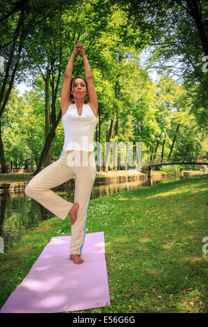Femme faisant de l'exercice de yoga dans un ancien parc Banque D'Images