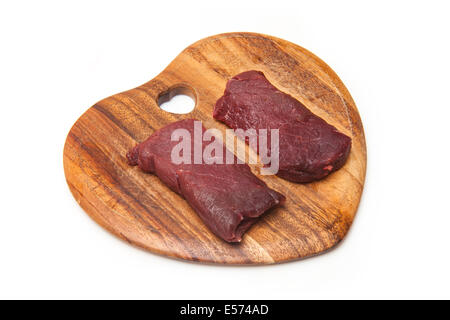 La viande de chameau steaks sur une planche à découper en bois isolé sur un fond blanc studio. Banque D'Images