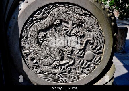 XIN XING VILLE, CHINE : Un médaillon sculpté en pierre avec dragon figure sur la base de la porte d'entrée de cérémonie Banque D'Images