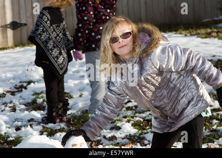 Snow fun en famille, jeune fille blonde portant des lunettes de faire boule de neige. Banque D'Images