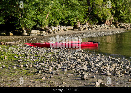 Deux kayaks rouges assis sur la côte rocheuse par l'eau et de la forêt du parc régional de Belcarra dans le Grand Vancouver, BC, Canada Banque D'Images