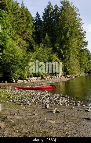 Deux kayaks rouges assis sur la côte rocheuse par l'eau et de la forêt du parc régional de Belcarra dans le Grand Vancouver, BC, Canada Banque D'Images