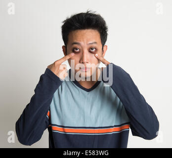 L'homme asiatique de l'insomnie, avec de grands yeux sac, sur fond uni Banque D'Images