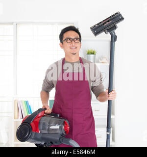 Asian man holding vide. Chambre mari faisant corvées maison, intérieur de la chambre. Banque D'Images