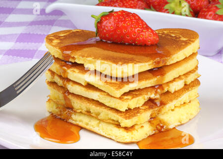 Des crêpes en forme de coeur avec le sirop et une fraise sur une assiette blanche. Un petit-déjeuner parfait pour la Saint-Valentin Banque D'Images