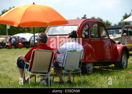 Hofheim-Diedenbergen, Allemagne. 23 juillet, 2014. Un couple est assis à côté d'un 'duck' (allemand : Ente, surnom pour Citroen 2CV) à la 6e Allemagne réunion des amis de la 2CV à Hofheim-Diedenbergen, Allemagne, 23 juillet 2014. Plus de 1 000 fans de la voiture culte français et environ 700 voitures sont attendus à la réunion. Photo : Arne Dedert/dpa/Alamy Live News Banque D'Images