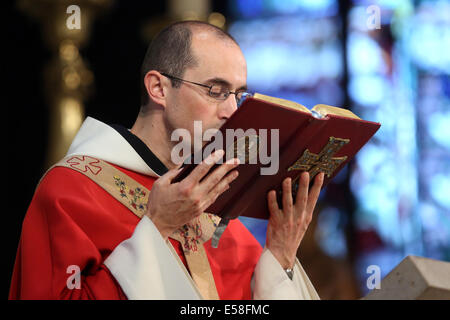 Prêtre catholique, embrassant la bible au cours d'un service dans une église catholique de Paris, France Banque D'Images