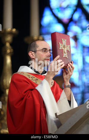 Prêtre catholique, tenant la bible au cours d'un service dans une église catholique de Paris, France Banque D'Images