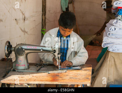 Le travail des enfants, couture garçon sur le stand sur le marché. Banque D'Images