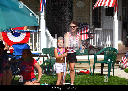 Fille et sa mère jouant avec hosepipe devant le porche le 4th juillet congé public du jour de l'indépendance, Catonsville, Maryland, Etats-Unis Banque D'Images