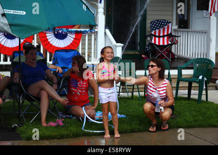 Fille et sa mère jouant avec hosepipe devant le porche le 4th juillet congé public du jour de l'indépendance, Catonsville, Maryland, Etats-Unis Banque D'Images