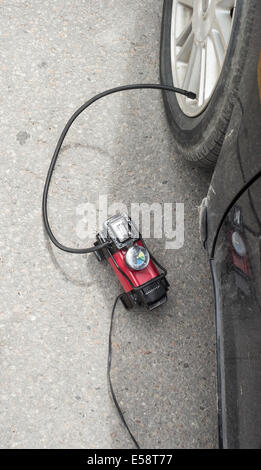 Compresseur d'air portatif de mettre l'air dans un pneu avant tout en étant connecté à la prise de courant dans la voiture. Banque D'Images