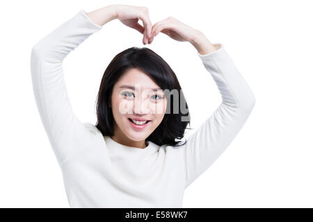 Cheerful young woman doing geste en forme de coeur Banque D'Images