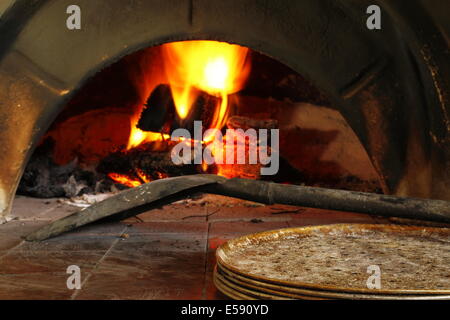 Sciage en feu dans un four à bois en préparation de la cuisson de la pizza. Banque D'Images