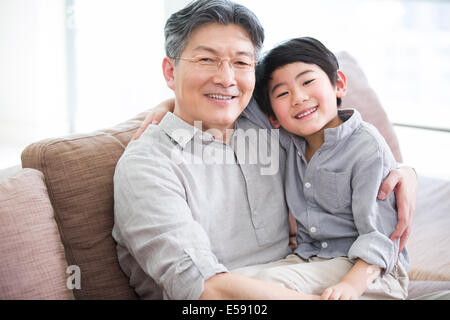 Mignon petit-fils assis sur les genoux de grand-père Banque D'Images